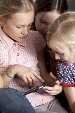 Drei Mädchen schauen auf ein Tablet