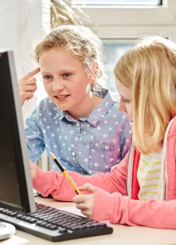 Zwei Mädchen tippen am Laptop